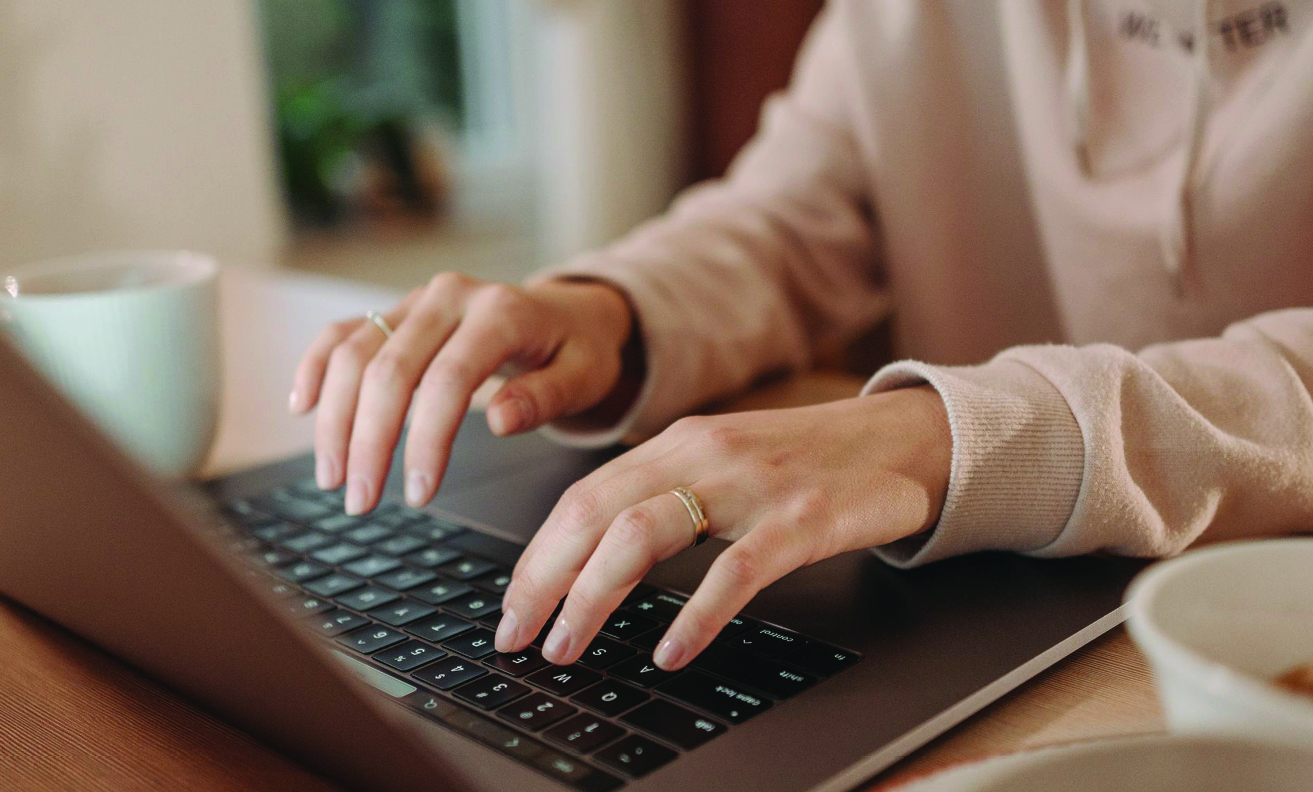 A person typing on a laptop, only their hands are visible.