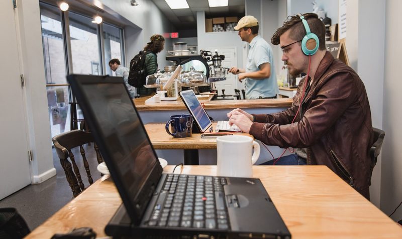 Virginia Tech male student studying with headphones on in a coffee shop.